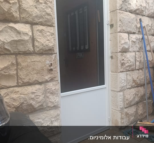 דלת אלומיניום לבנה מותקנת בקיר אבן